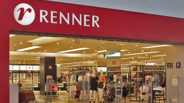 Entrada de uma loja Renner vista do corredor do shopping, com o letreiro vermelho iluminado